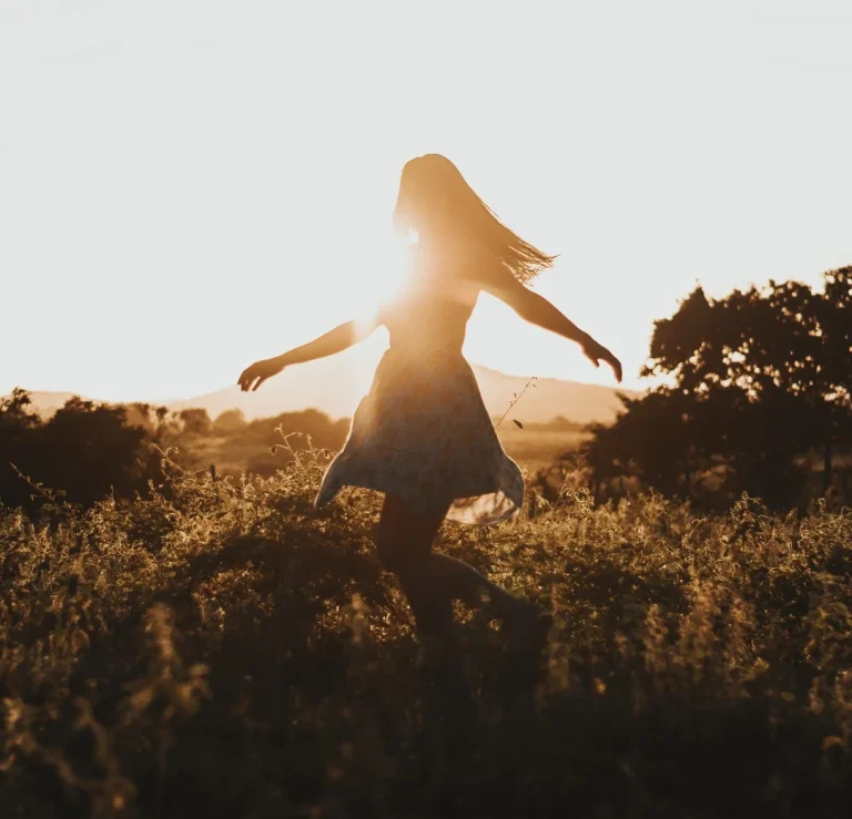 Eine Frau dreht sich im Sonnenuntergang auf einem Feld.