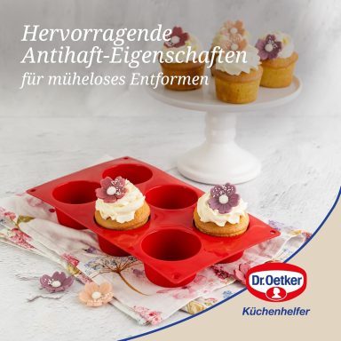 Rote Silikonform für Cupcakes mit Blumenverzierung, im Hintergrund auf einem Teller.