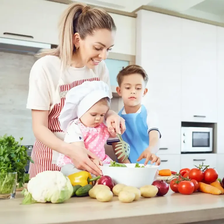 Eine Mutter bereitet mit zwei Kindern gemeinsam eine Mahlzeit in der Küche vor.