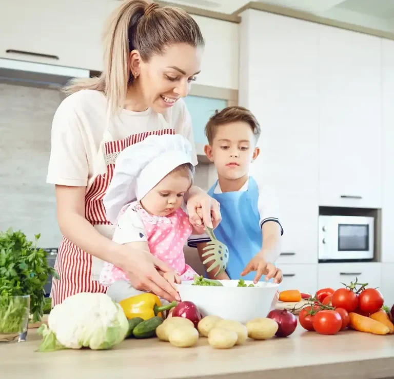 Eine Mutter bereitet mit ihren Kindern frisches Gemüse in der Küche vor.