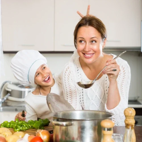 Eine Mutter und ihr Kind kochen zusammen in einer modernen Küche, voller Freude und Spaß.