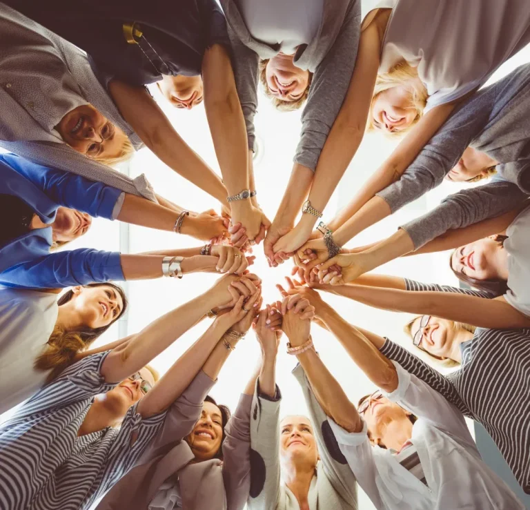 Gruppierung von Händen, die sich in der Mitte treffen, um Zusammenarbeit zu symbolisieren.