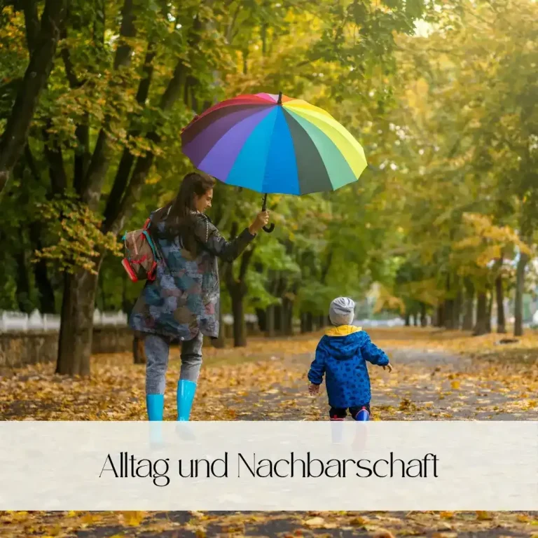 Eine Frau mit buntem Regenschirm geht mit einem kleinen Jungen in einem herbstlichen Park.