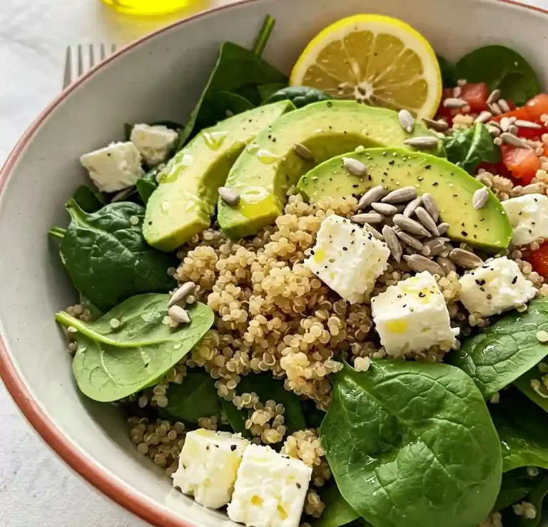 Schüssel mit Quinoa, Spinat, Avocado, Tomaten, Feta, Sonnenblumenkernen und Zitrone.