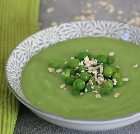 Grüne Erbsensuppe mit Erbsen und Haferflocken in einer dekorativen Schüssel.