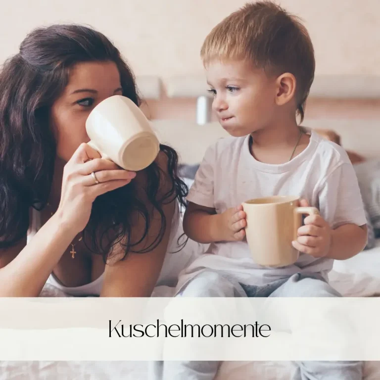Mutter und Kind sitzen entspannt mit Tassen auf dem Bett und genießen Zeit miteinander.